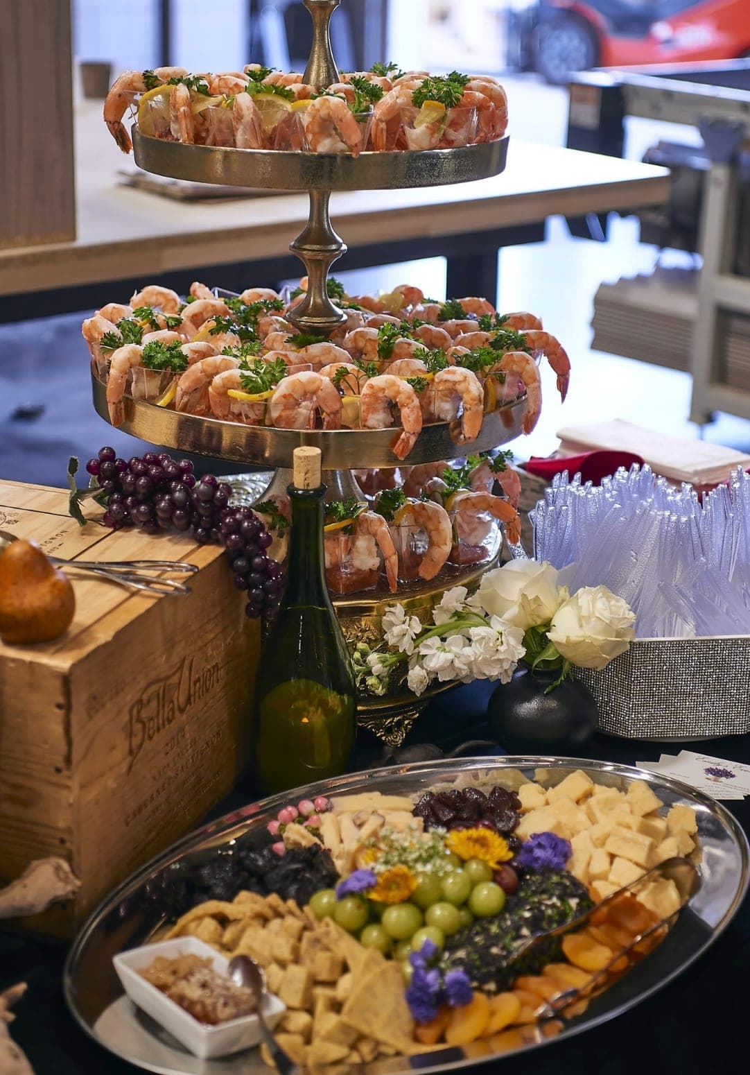 Tiered shrimp cocktail display with a charcuterie and cheese board