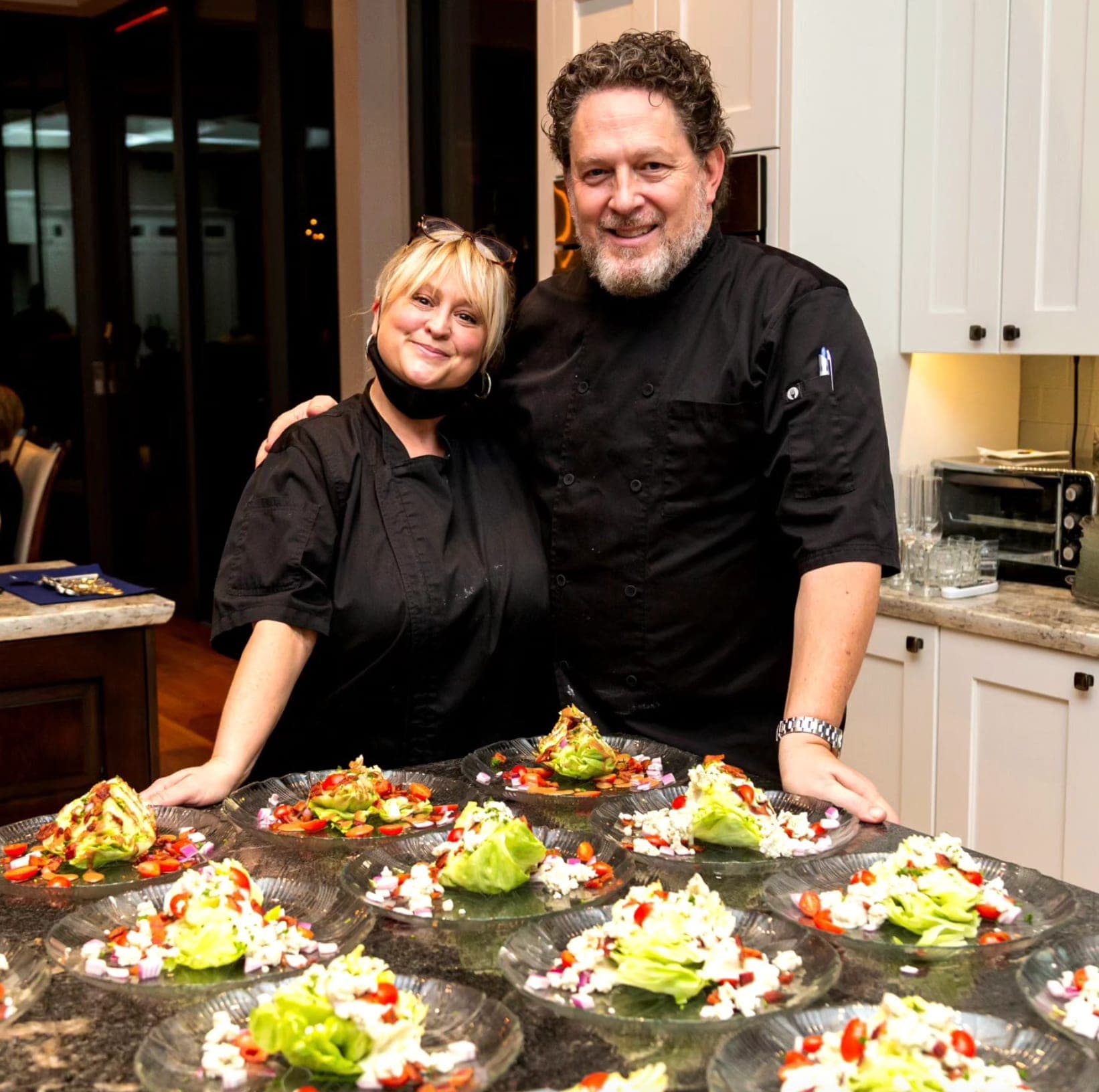 Emily and Rick in chef blacks behind a spread of plated wedge salads