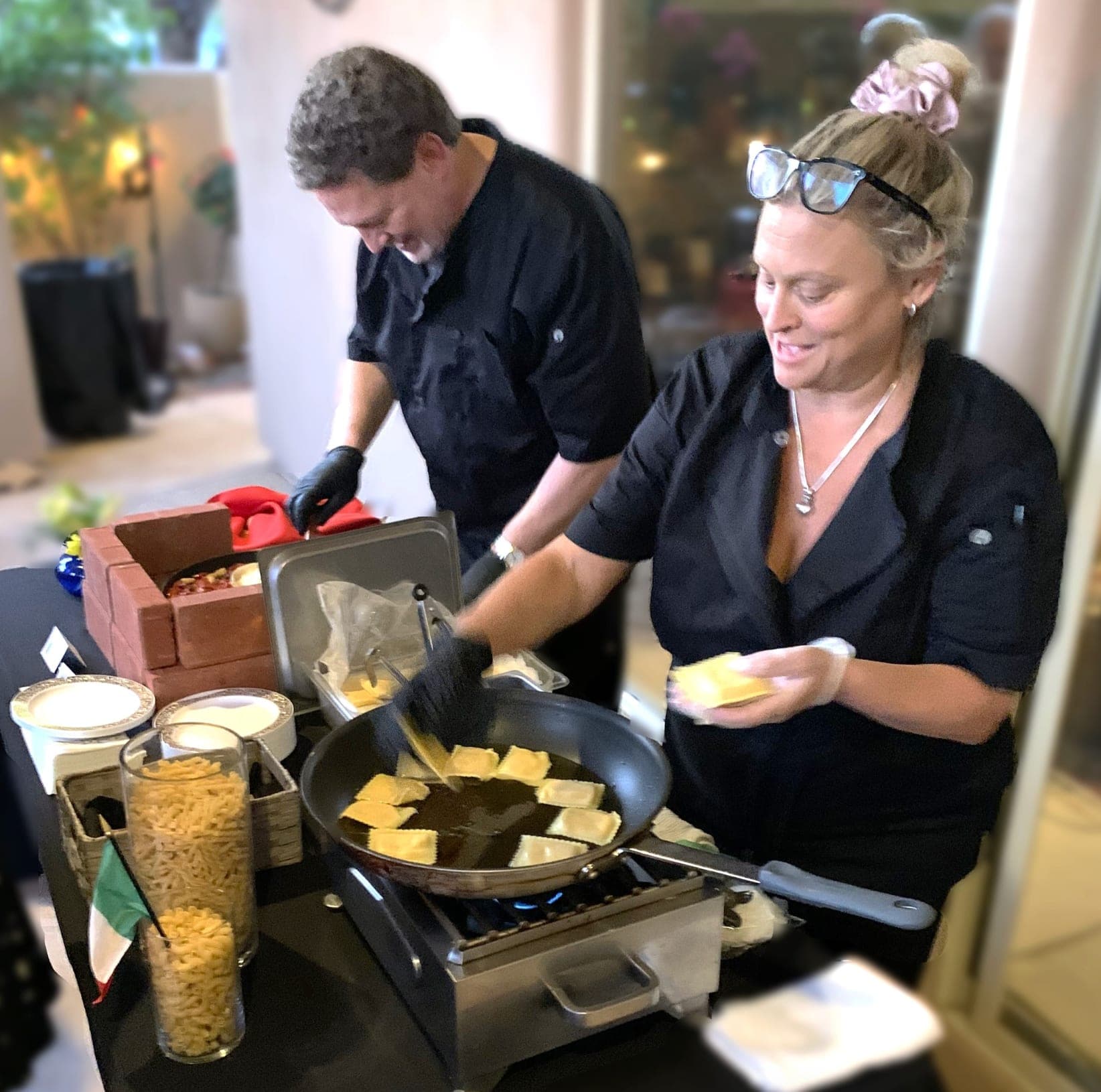 Emily and Rick working a pasta station, searing ravioli to order