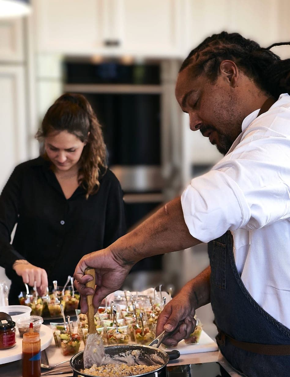 Staff assembling appetizer cups in a kitchen during service