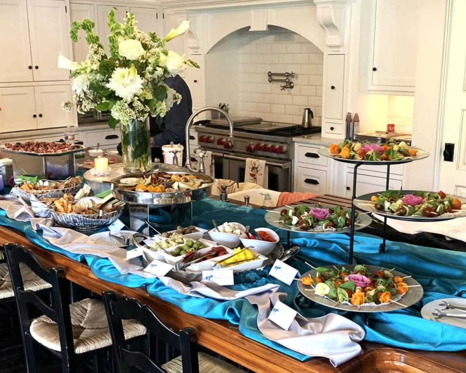 A grazing buffet with tiered skewers and florals on a home kitchen island