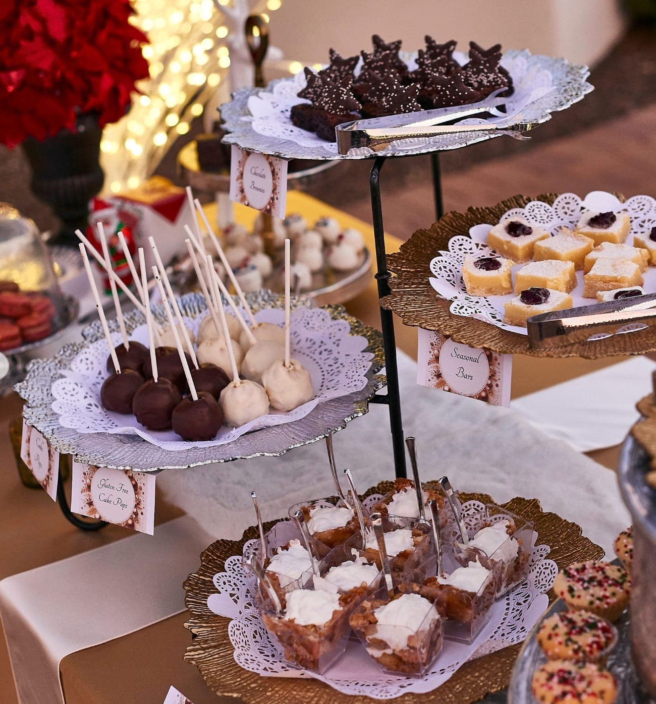 A tiered holiday dessert display with cookies, cake pops, and bars