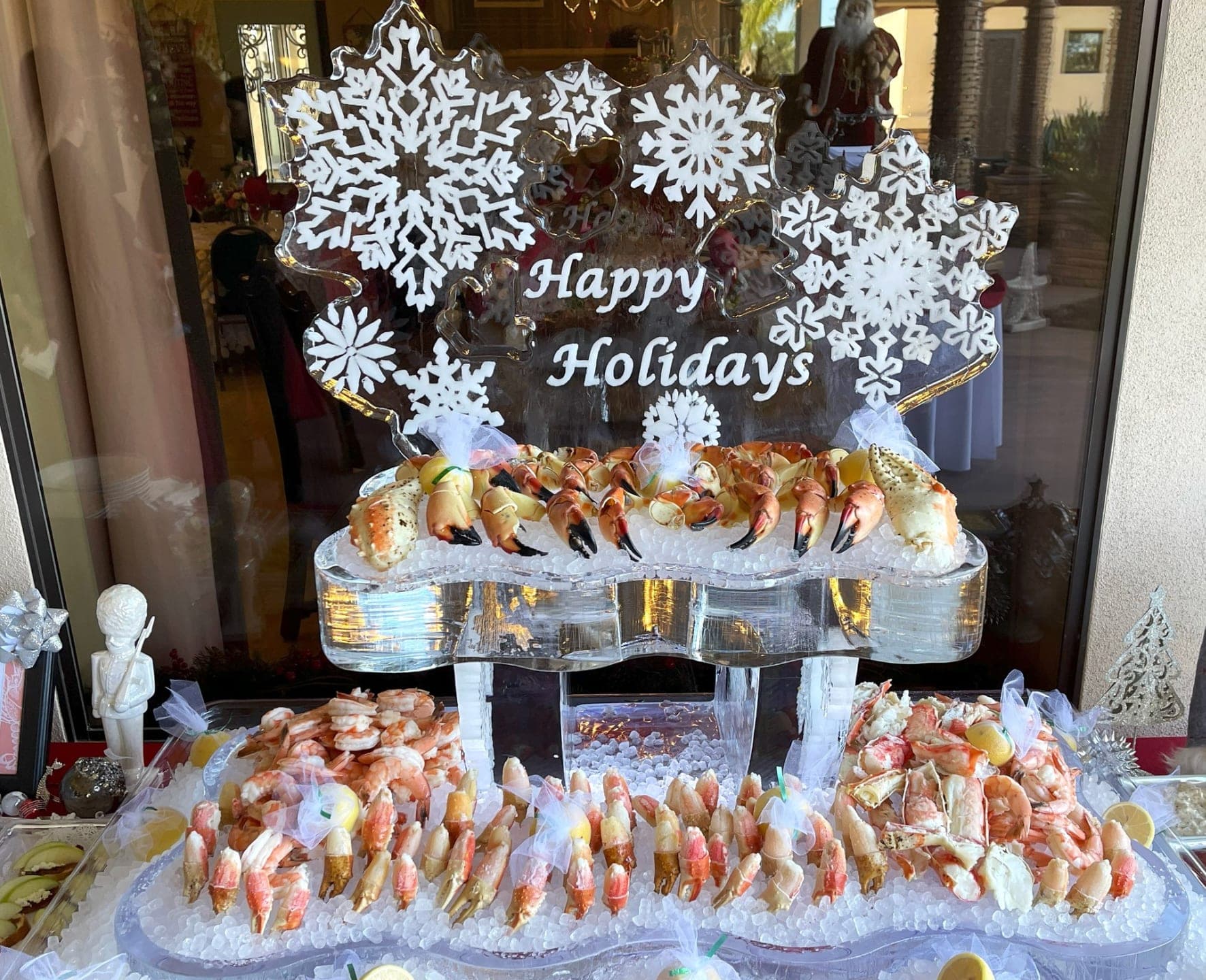A 'Happy Holidays' ice sculpture above a chilled seafood display