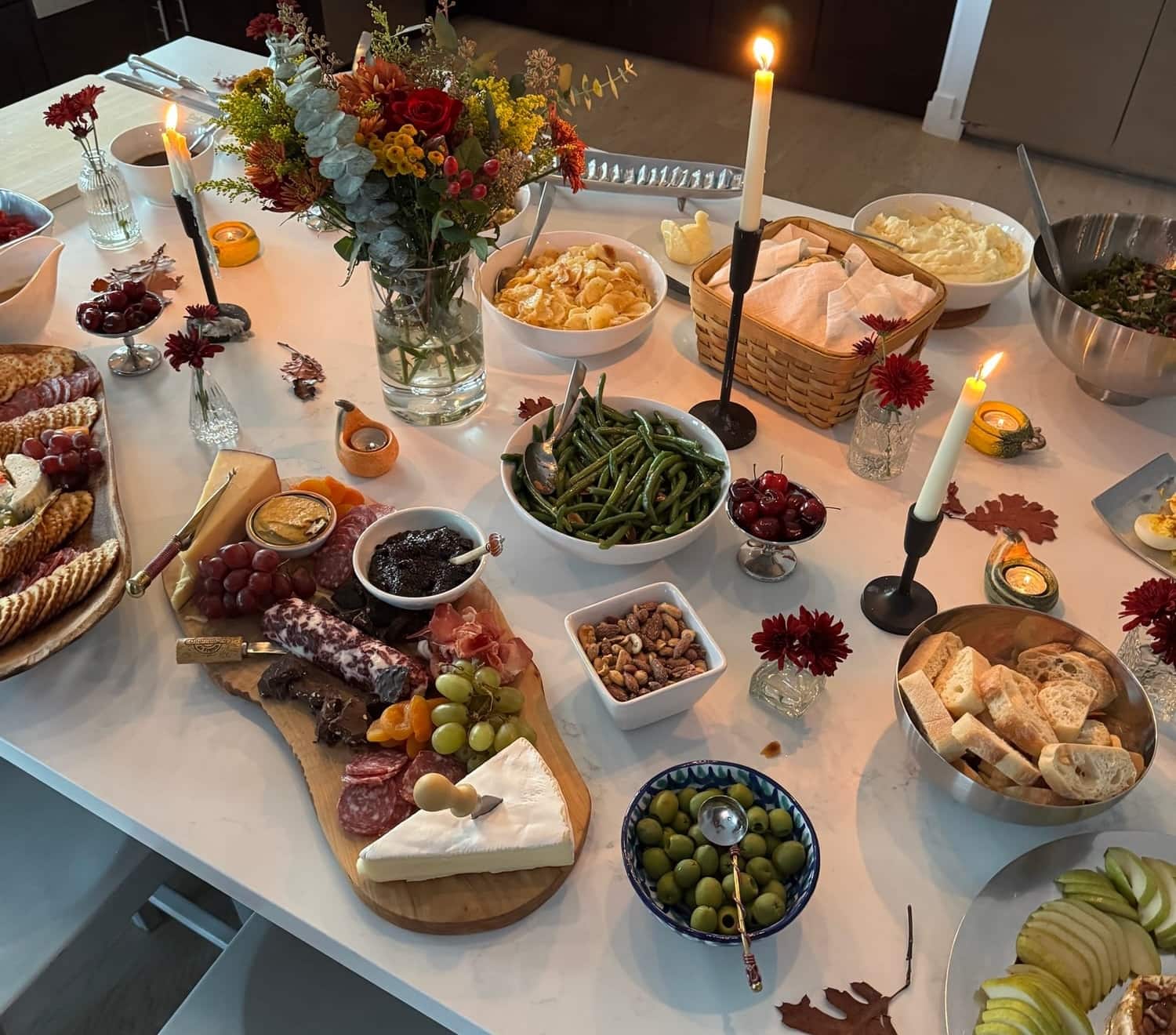 Overhead view of a holiday spread — mashed potatoes, green beans, breads, and fall florals on a marble island