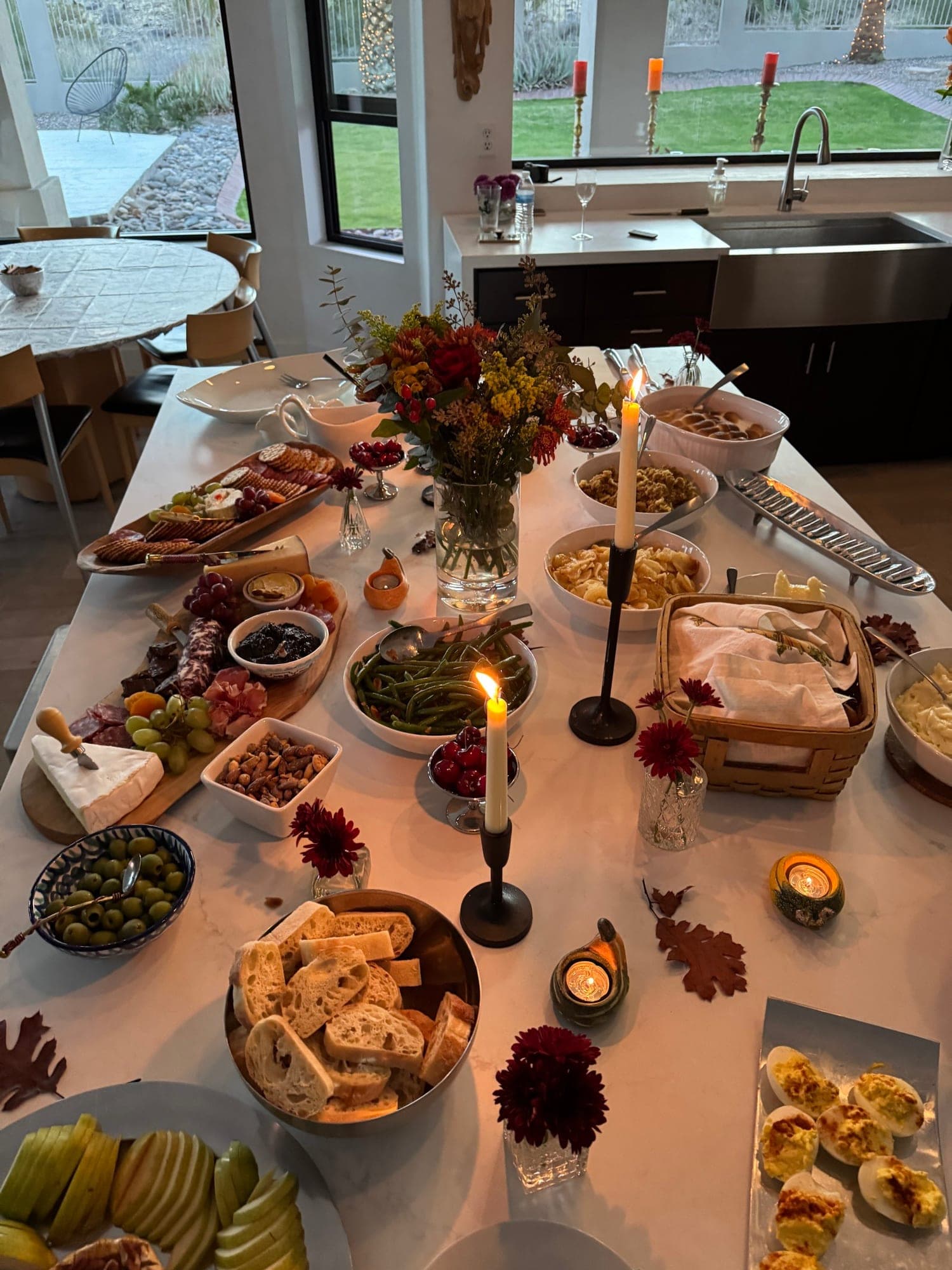 A candlelit holiday table set toward the kitchen