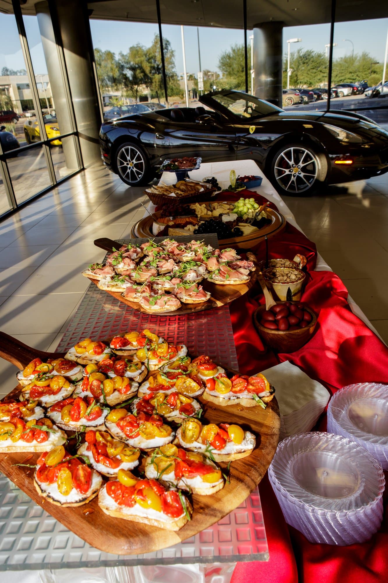 Catering spread in a luxury car showroom beside a sports car